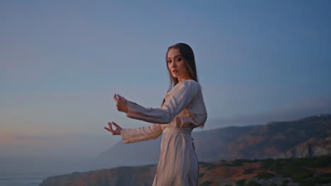 bailarina flexible con las manos en movimiento colinas al atardecer naturaleza primer plano. mujer bailando acantilados