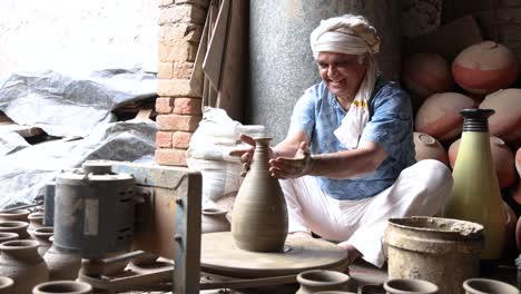 old man making clay pot on spinning wheel