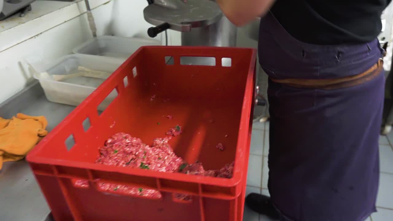 carnicero poniendo carne picada con especias en la máquina de hacer salchichas