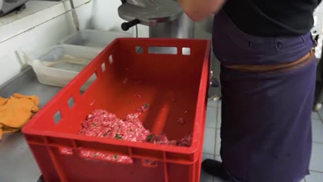 butcher putting minced meat with spices into sausage making machine