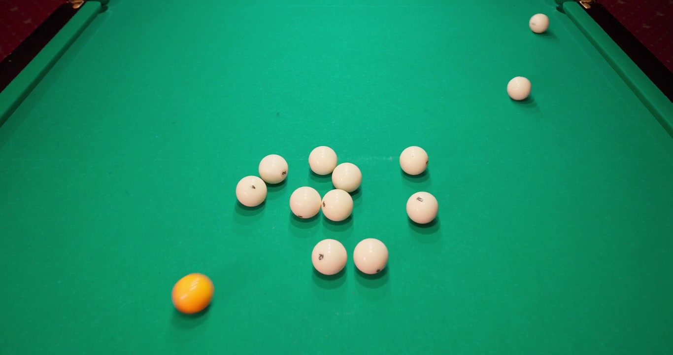 Orange Cue Ball Breaking a Rack of White Billiard Balls