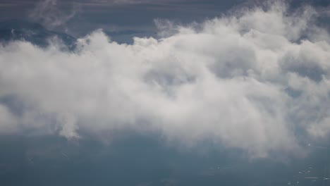 vuelo a través de las densas nubes blancas girando sobre las montañas cubiertas de nieve y un sombrío valle oscuro