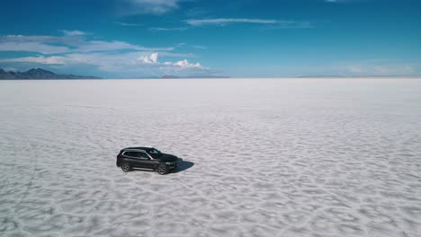 El-Video-Cinematográfico-De-Un-Dron-Rastreando-Un-Automóvil-Desde-El-Costado-En-Un-Control-Remoto-Es-Como-Un-Desierto-A-Alta-Velocidad,-Salinas-De-Bonnesville,-Utah,-Clip-Aéreo-De-EE