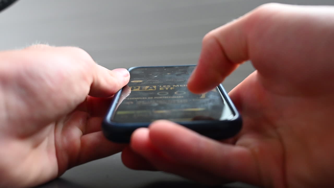 un usuario de teléfono se desplaza por un medio en su móvil, perdiendo el tiempo con esta adicción moderna