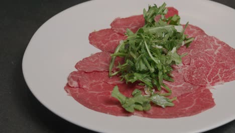 Arugula-is-delicately-placed-atop-Japanese-A5-beef-on-a-plate,-adding-a-fresh-touch-to-the-gourmet-dish