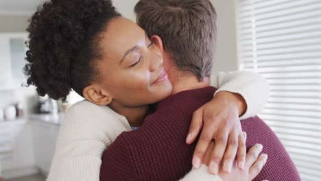 Video-of-happy-diverse-couple-hugging-in-kitchen