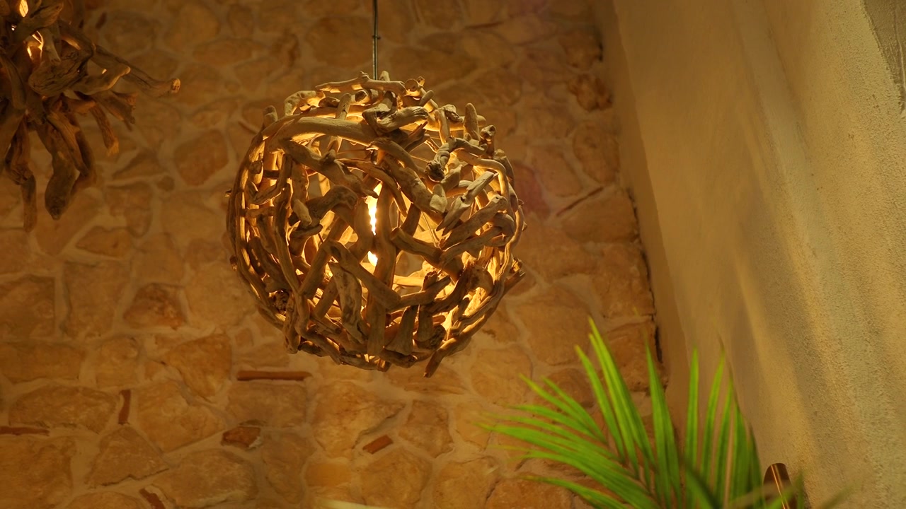 Lampada a sospensione decorativa a sfera in legno di recupero appesa a una parete in pietra