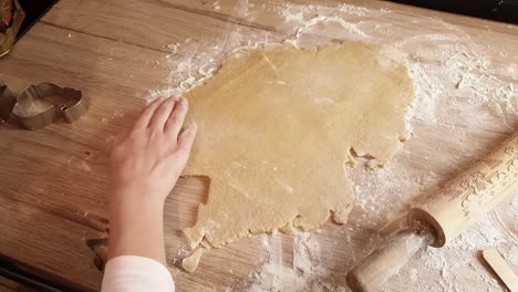 young girl uses sugar cookie templates to cut cookies out of raw dough