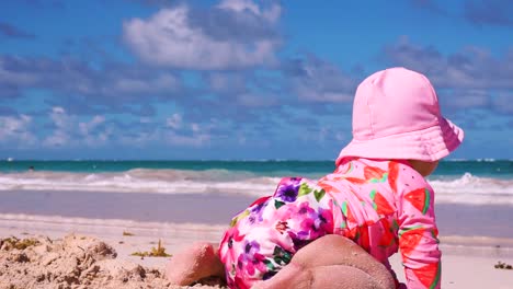 happy baby girl crawling and playing in sand bávaro beach close up get out of frame waves and sunny cloudy sky hd steady shot