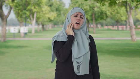 sick muslim woman suffering from tooth pain in park