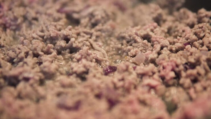 Timelapse de carne moída com cebolas dourando de vermelho a marrom, em close-up