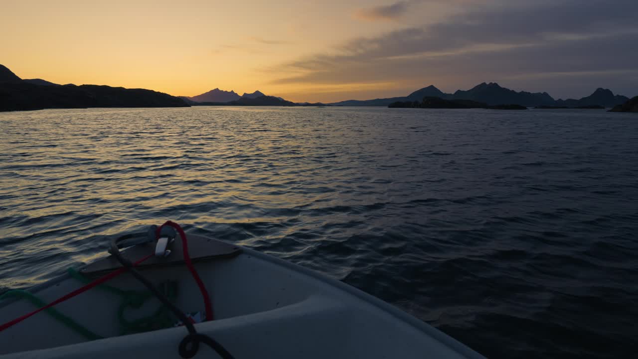 Boat trip with a small boat towards the islands on a bright and calm summer night. Lofoten, Northern Norway