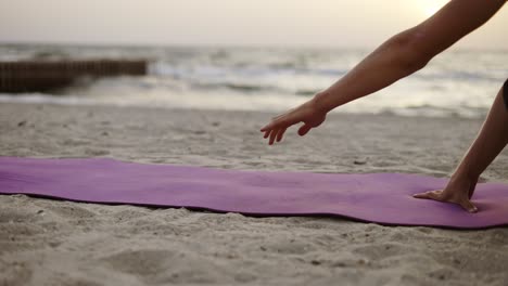 A-young-man-lays-out-a-sports-mat-and-prepares-for-a-yoga-class-during-the-dawn-of-the-son.-Leisure-time,-recreation.-Close-up