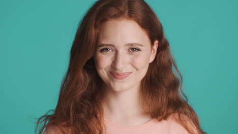 Redheaded-girl-in-front-of-camera-on-turquoise-background.