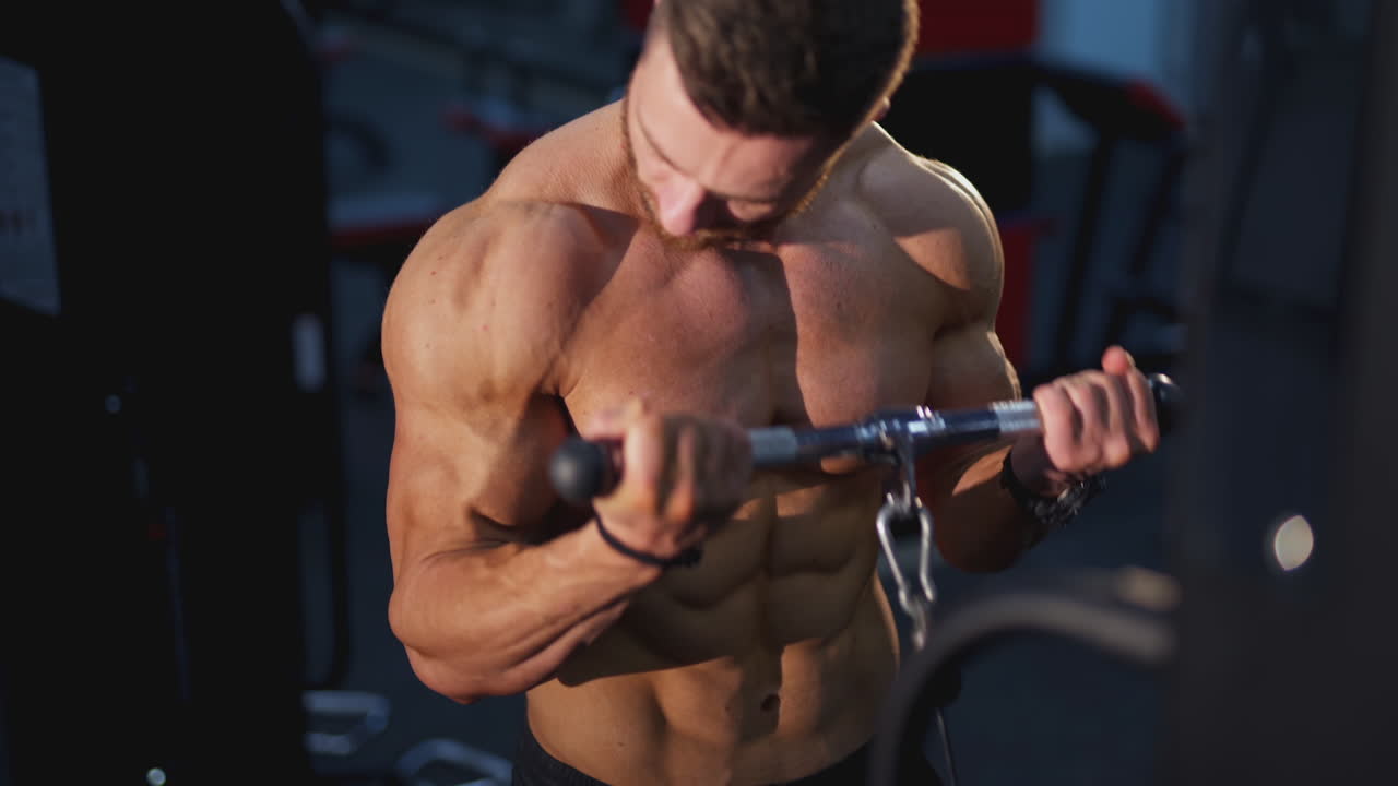 Training muscles. Sportsman pumping his trained body on a simulator. Strong trainer doing workout. Exercise to improve strength at fitness club. Close-up.