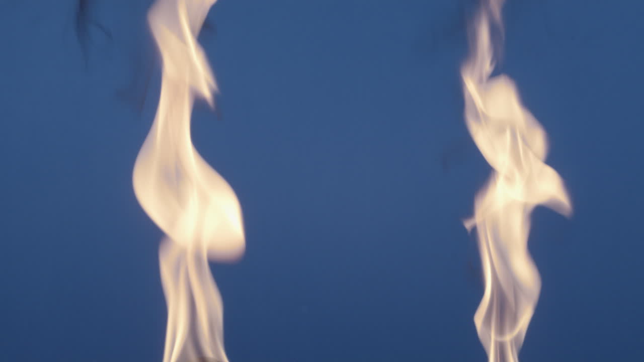 Two Tall Flames Burning Bright Against a Blue Night Sky