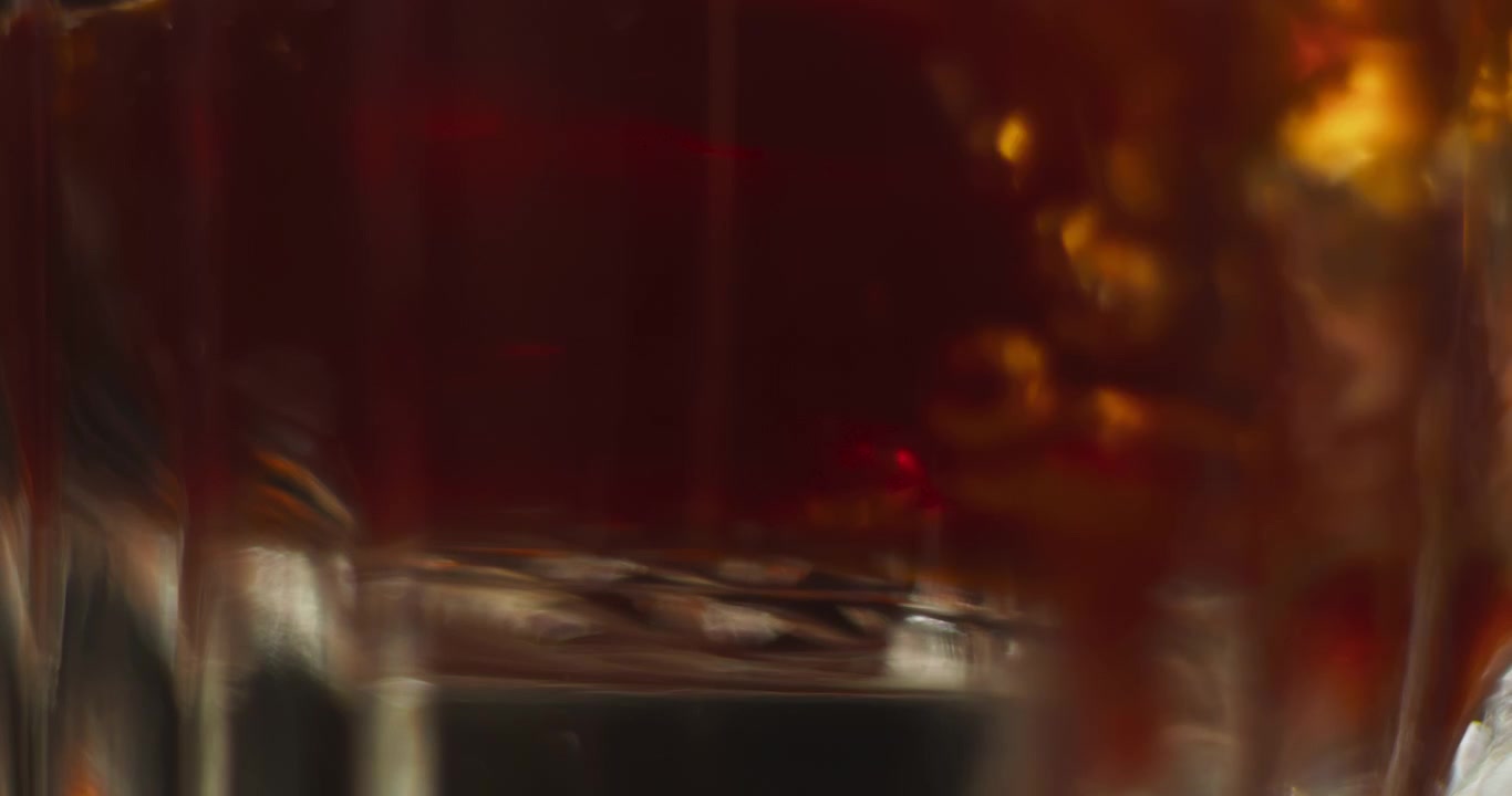 Primo piano macro estremo di whisky scuro versato in un bicchiere dal design ornato