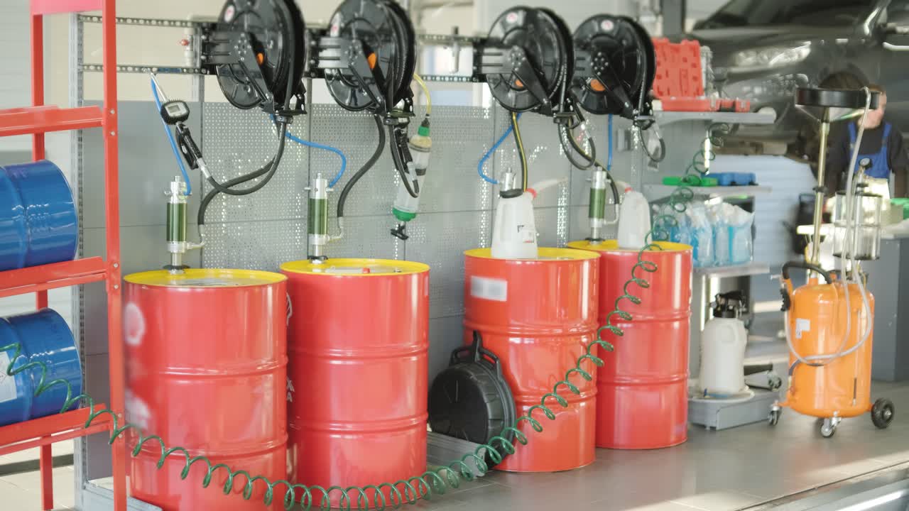 현대 자동차 서비스 워크에서 끔하게 배열 된 은 오일 배럴, 조직 된 장비와 함께 산업 설정, 전문 자동차 유지 보수 및 저장 솔루션을 강조합니다.