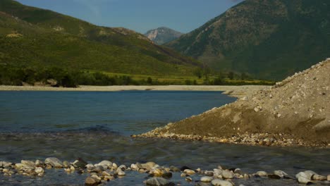 creek water streaming into river of vjosa with mountains background in albania