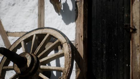 old wood wheel and black door at white house