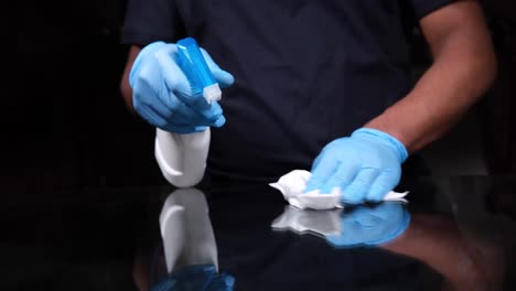 cleaning a black surface with spray bottle and gloves