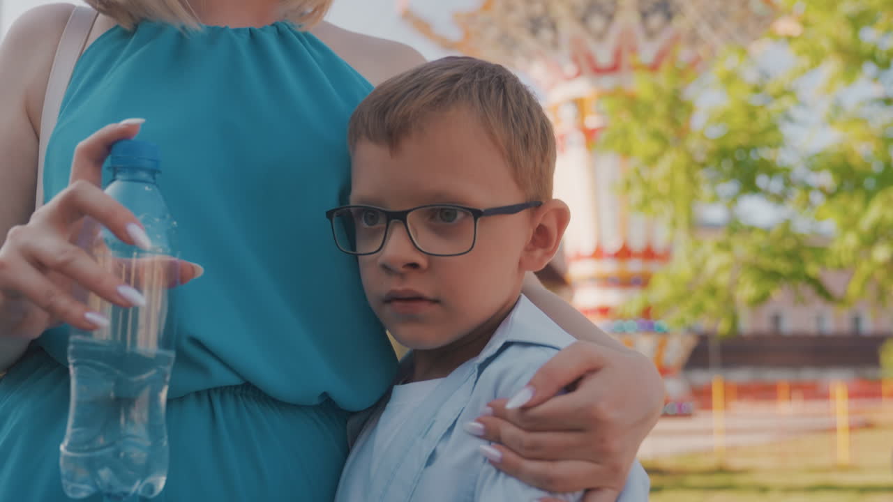 Madre che calma il bambino. Una madre premurosa conforta teneramente il suo vivace bambino all'aperto con abbracci. La madre abbraccia affettuosamente e calma il suo energico figlio piccolo durante il gioco all'aperto usando dolci abbracci.
