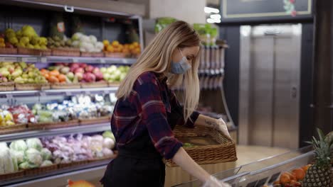 Trabajadora-Con-Delantal-Negro-Y-Máscara-Almacenando-Aguacates-Frescos-En-El-Supermercado