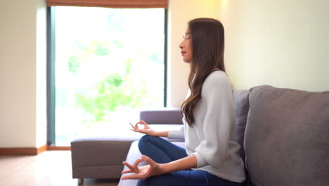 Close-up-of-Asian-adult-woman-in-yoga-lotus-position-and-meditation-indoor-activity-at-home---concept-of-healhty-and-relaxed-lifestyle-people