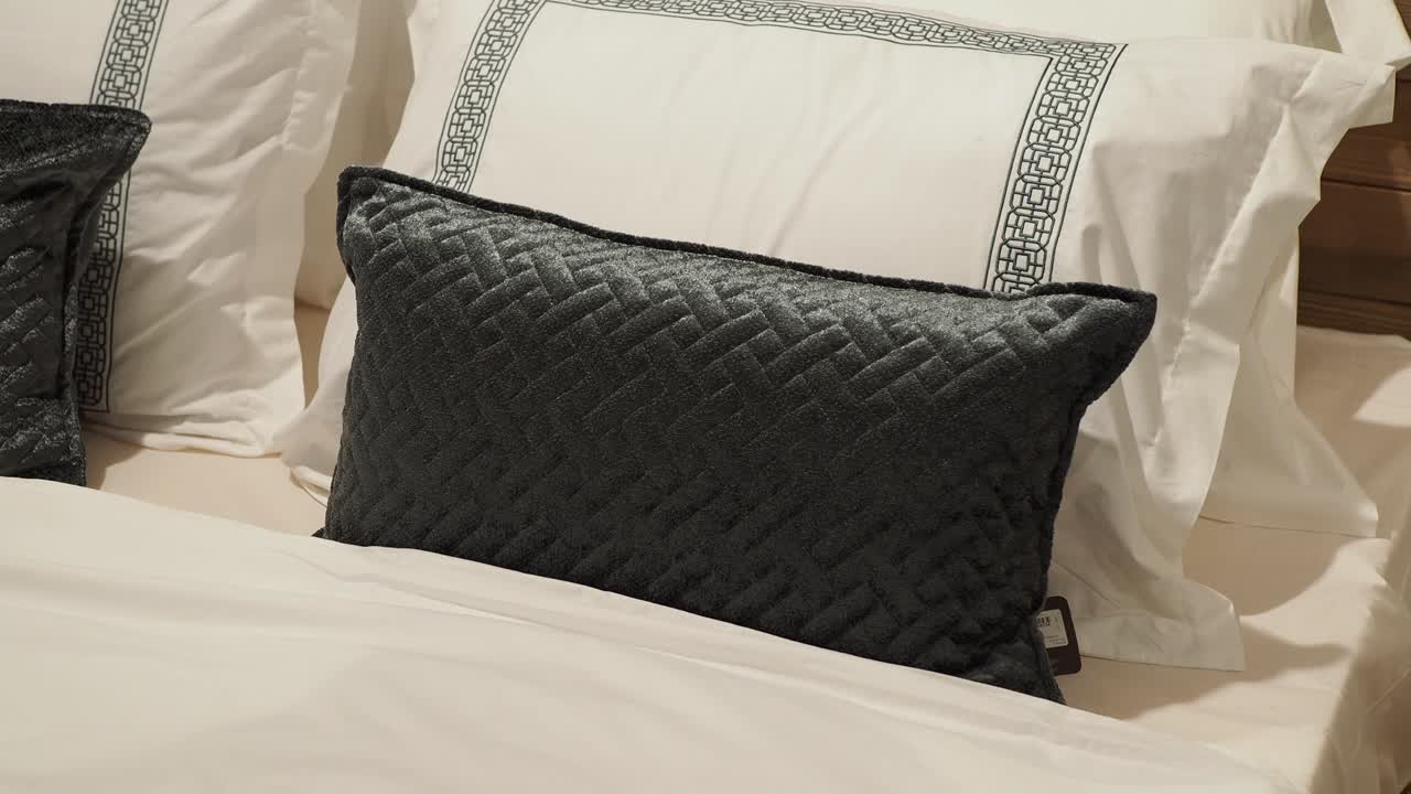 almohada elegante de color gris oscuro en una cama blanca