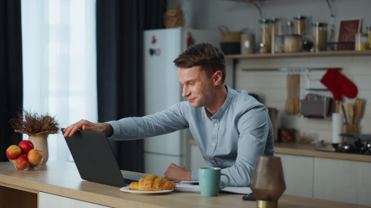 Man saying goodbye webcam finishing video call in kitchen. Guy closing laptop.
