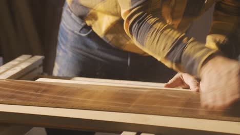 carpenter measures dusty wood with meter.