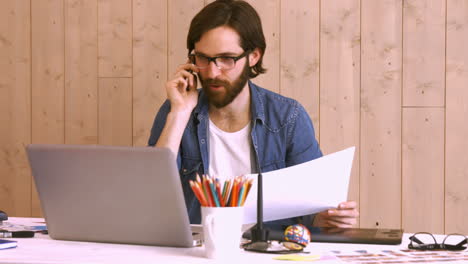 Casual-worker-phoning-at-his-desk-using-laptop