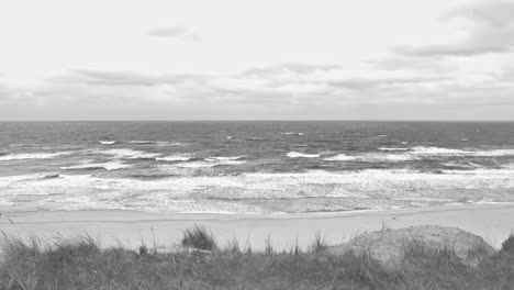 waving sea with the view over a dune at a beach in black and white