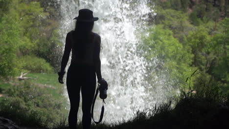 silueta de mujer caminando en cueva bajo cascada
