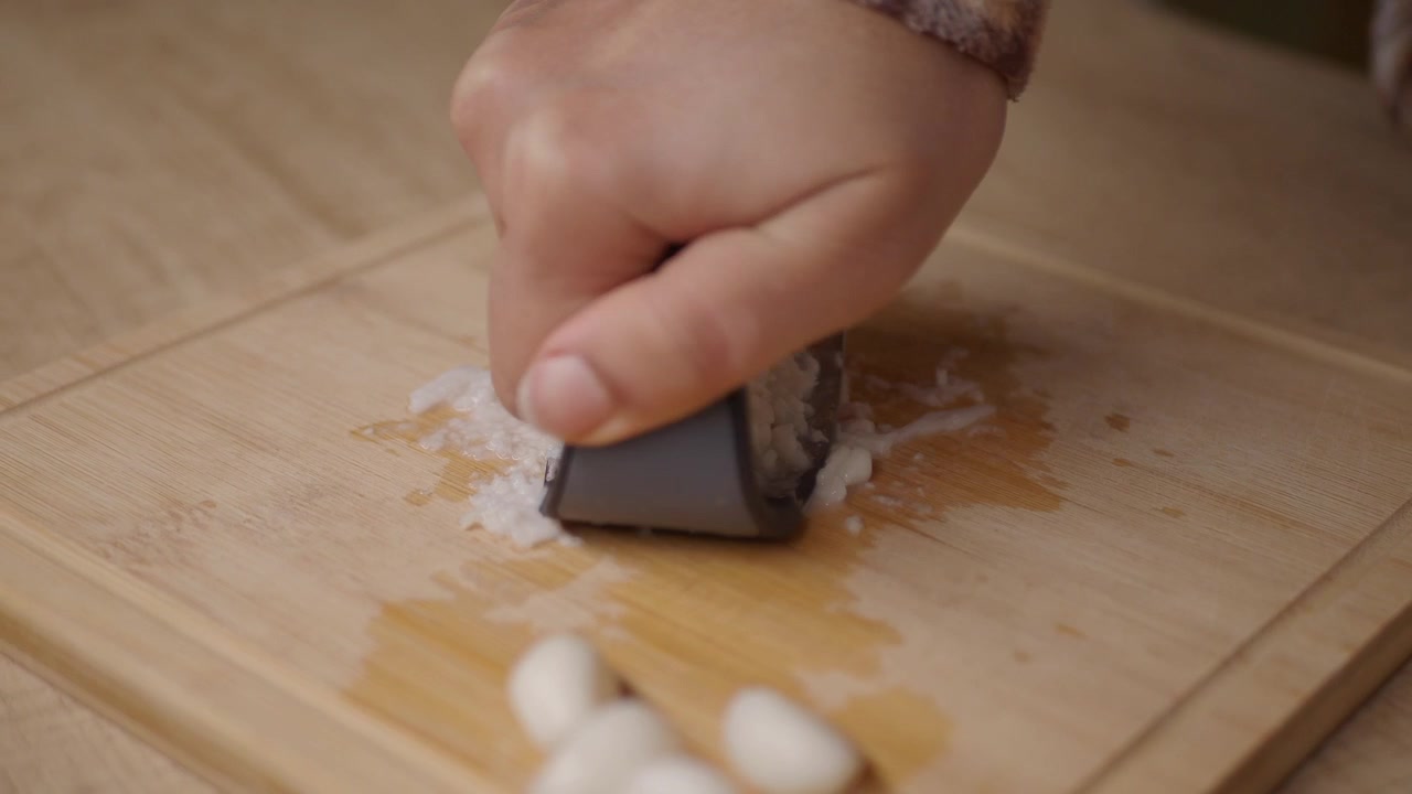 Persona che usa uno spremiaglio su un tagliere di legno