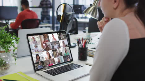 mujer caucásica teniendo una videoconferencia con colegas de oficina en una computadora portátil en la oficina