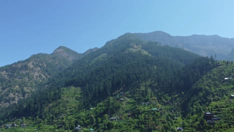 aerial view short of jibhi himachal pradesh in india. houses and trees in the mountainous area. faguli festival is one of the biggest festival in jibhi. the traditional houses here have stone roofs.