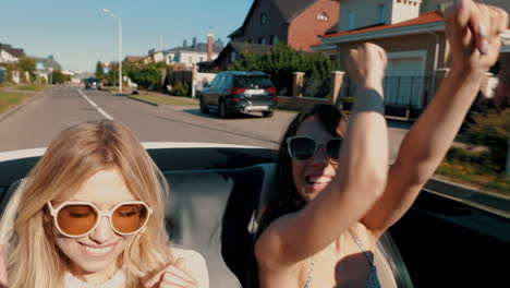 dos mujeres disfrutando de un paseo en un coche convertible