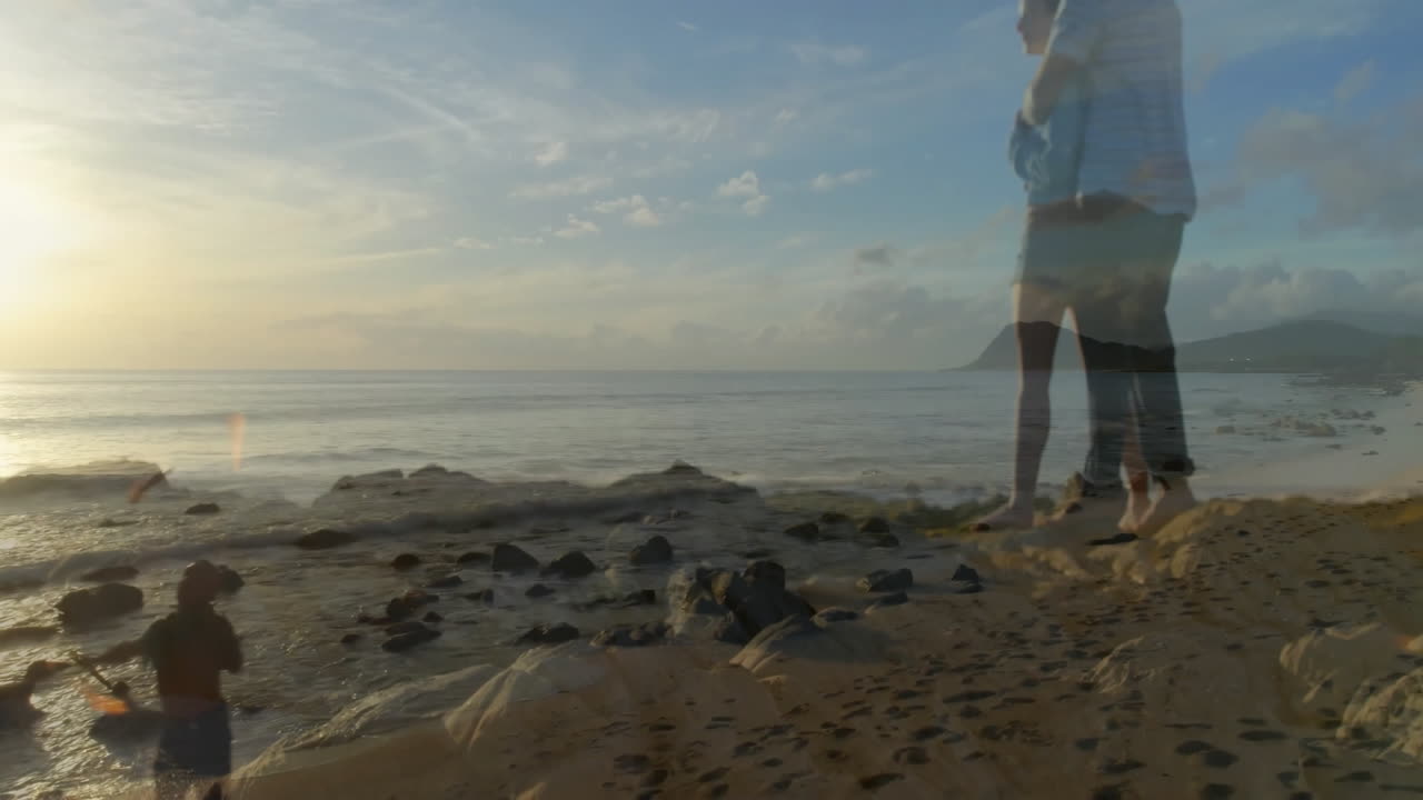 Standing on rocky beach, person watching ocean waves and sunset in background