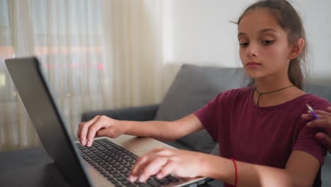 close up of girl typing on laptop while person beside her taps her arm to get attention she pauses glances over to check what he is doing then smiles and gives supportive thumbs up
