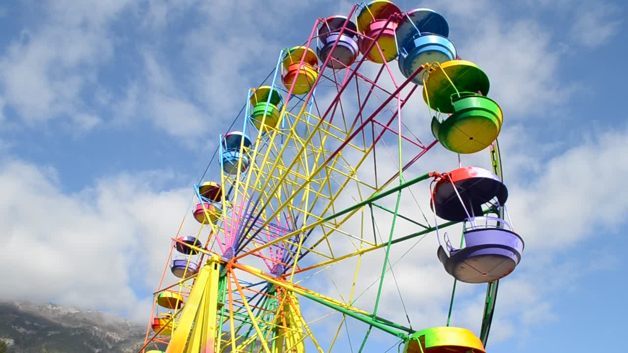 big wheel with multicolored cabins in amusement park