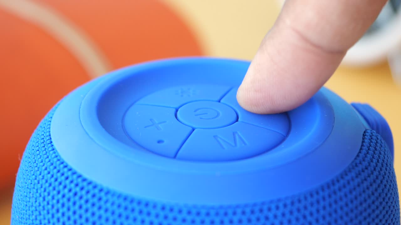 persona ajustando el volumen en un altavoz bluetooth portátil