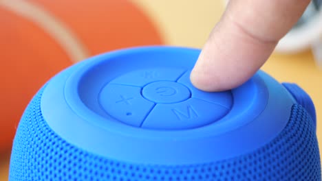 person adjusting volume on a portable bluetooth speaker