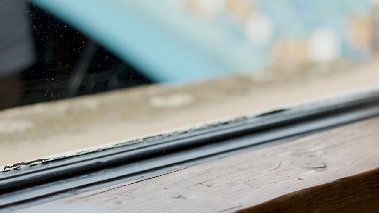 A hand sets a cappuccino on a wooden window ledge in a bright, modern cafe