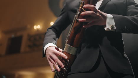 músico con fagot en la escena de la casa de la ópera o el salón filarmónico primer plano de las manos