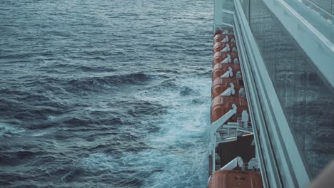 static shot of waves crashing on the side of a large cruise liner as it sails through the indian ocean