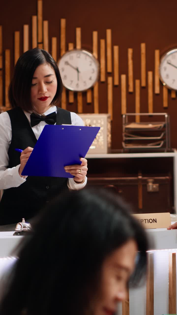 Video verticale: un ospite di un hotel firma i documenti di registrazione alla reception