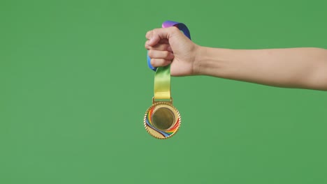 medalla de oro en la mano. fondo de pantalla verde