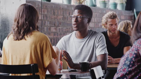 young couple meeting sitting at table in coffee shop and talking