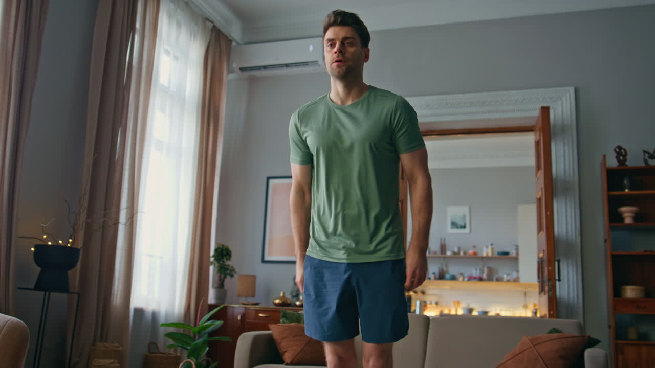 Athletic man workout home. Focused strong guy doing forward lunge exercises